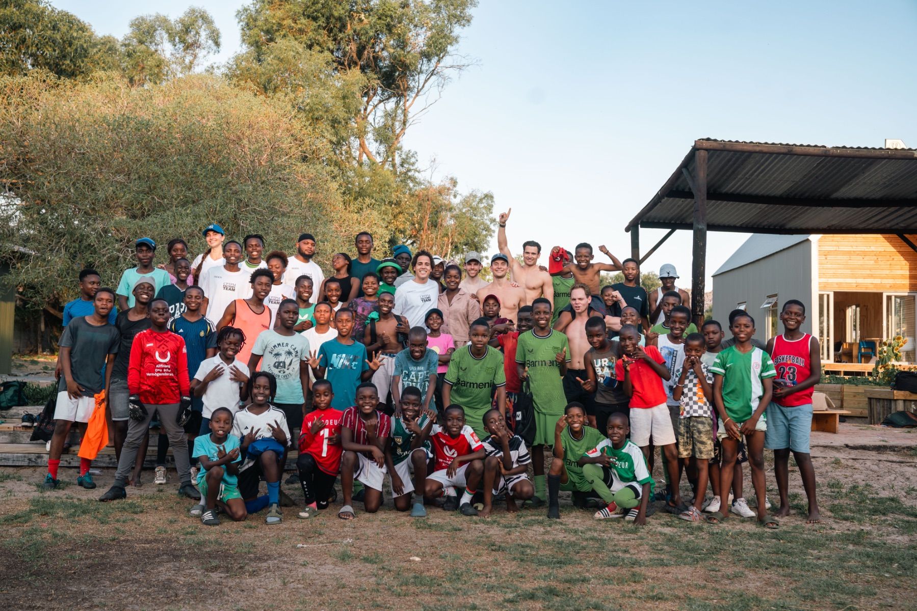 Volunteers and children from Mon Coeur’s school gathered for a group photo outdoors