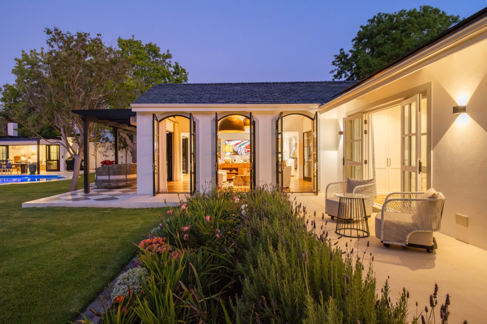 Russet Rise at dusk, its pool and lawn lit against the house.