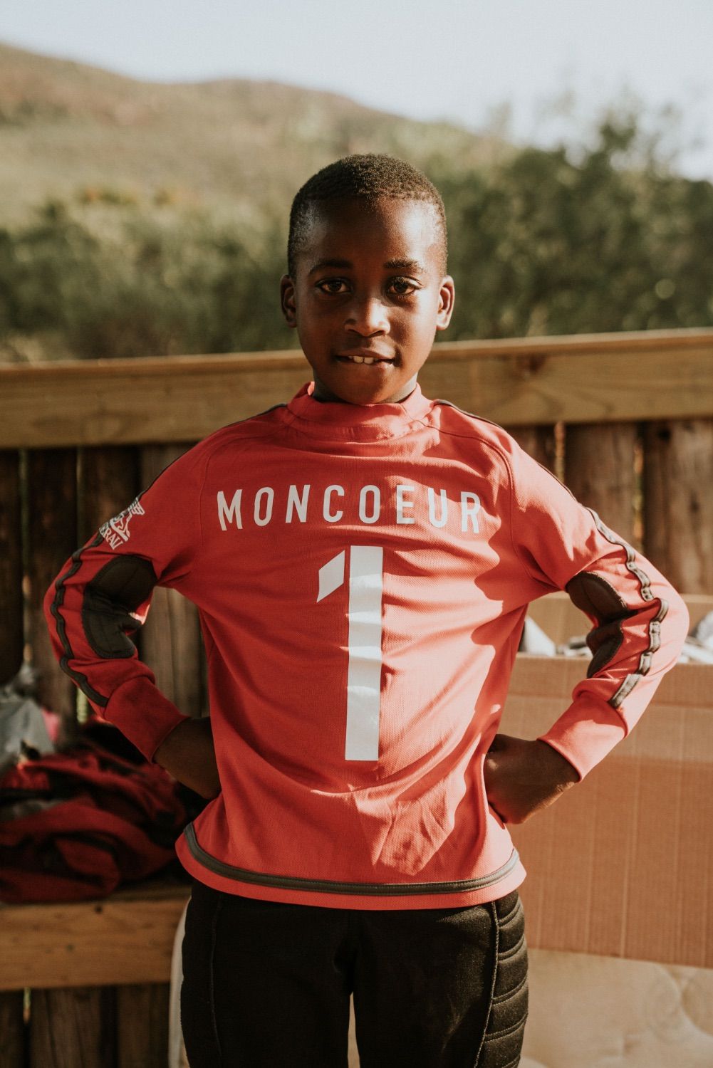 A boy in a red Mon Coeur football shirt with the number one, hands on his hips