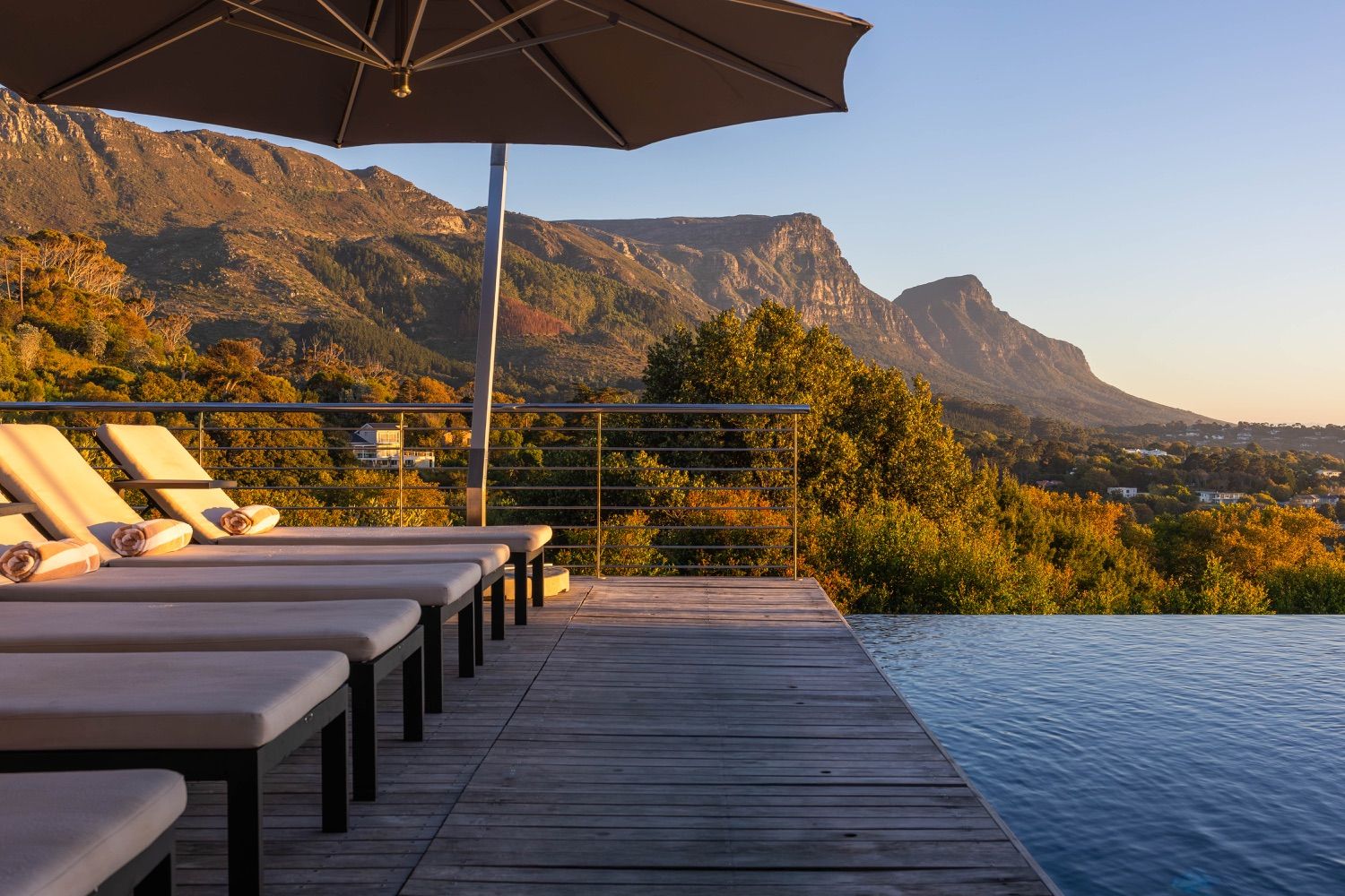 Sun loungers beside an infinity pool at golden hour, with the mountain behind