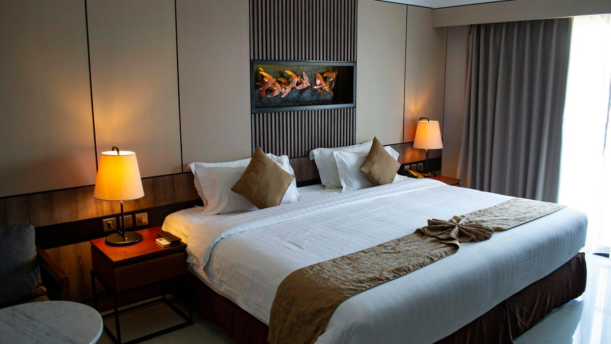 Hotel guest room with a bed dressed in white linen