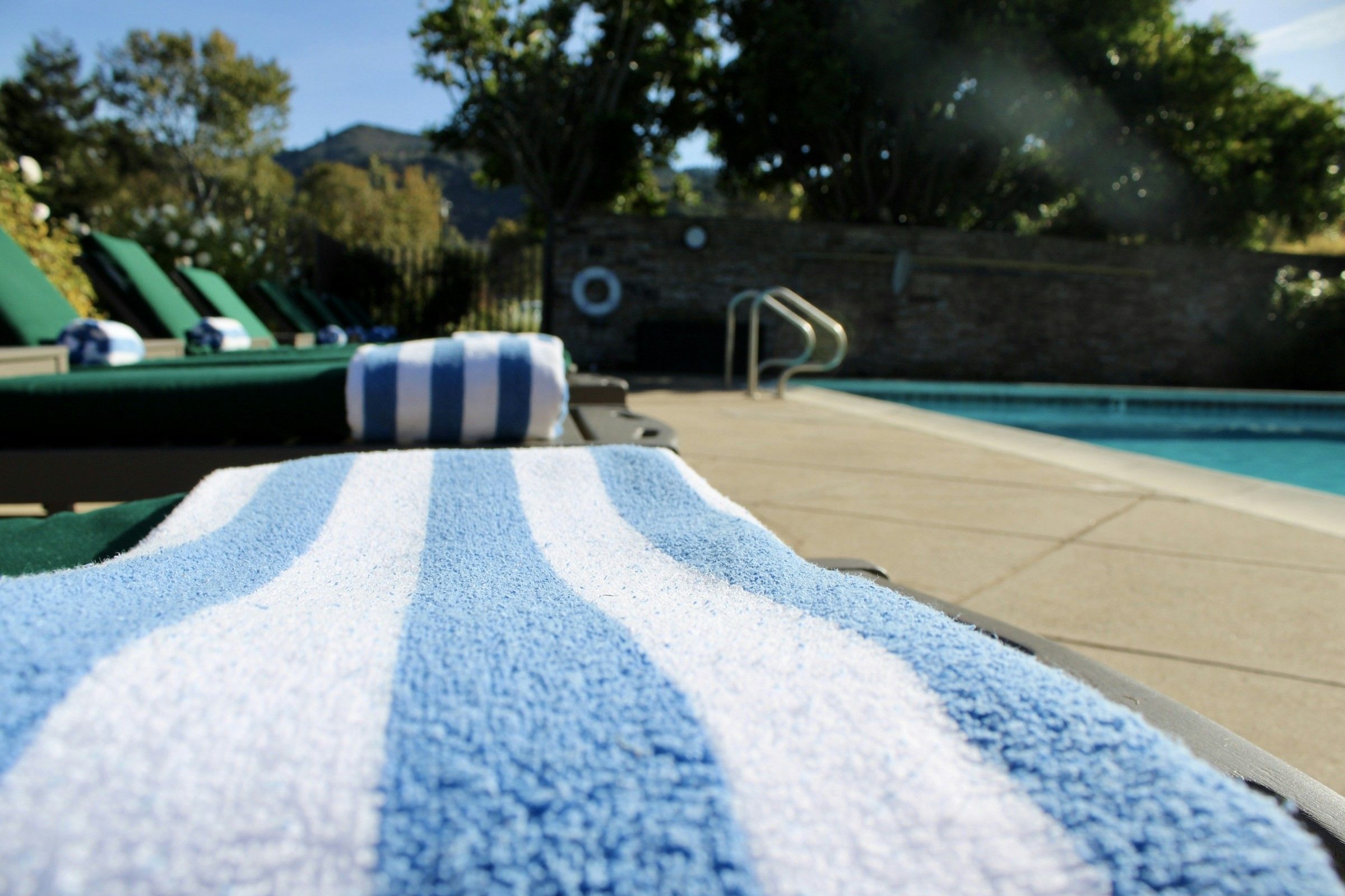Blue and white striped pool towel on a lounger beside a hotel swimming pool