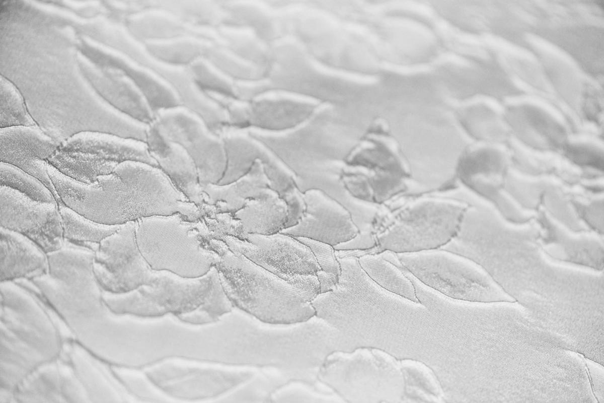 Close-up of white jacquard fabric with a raised floral pattern