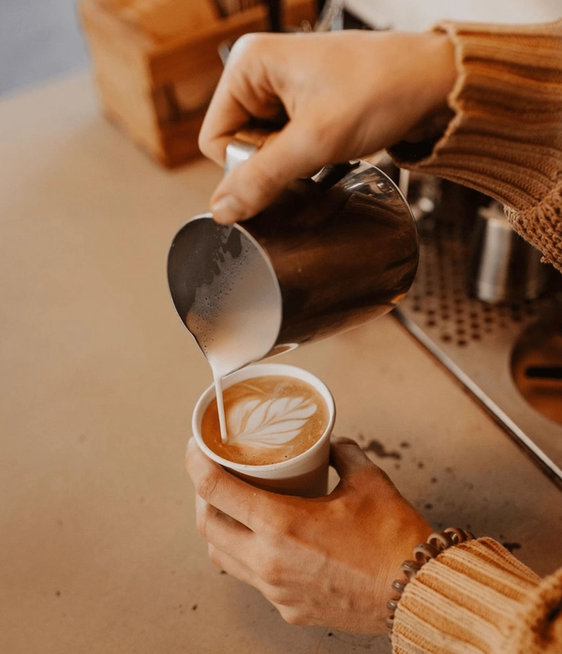 A close up of a barista pouring a beautiful latte.