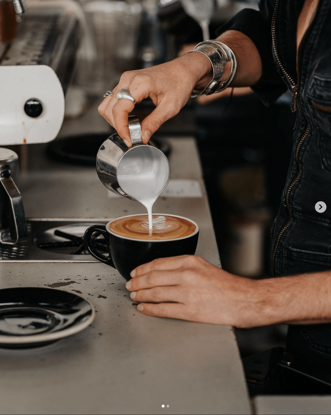 Close up of a baristas hands pouring a latte. 