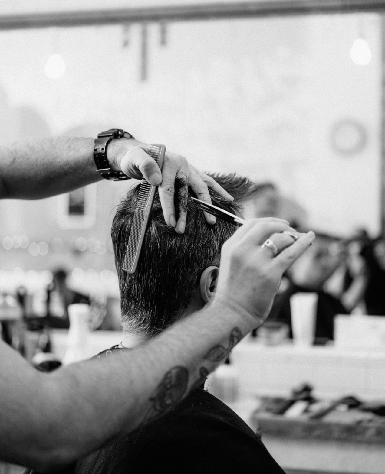 Black and white picture of a man getting a haircut at Rudy's. 