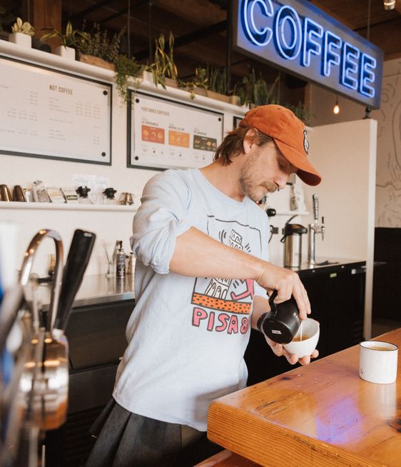 An employee is making a cup of coffee at Water Avenue Coffee