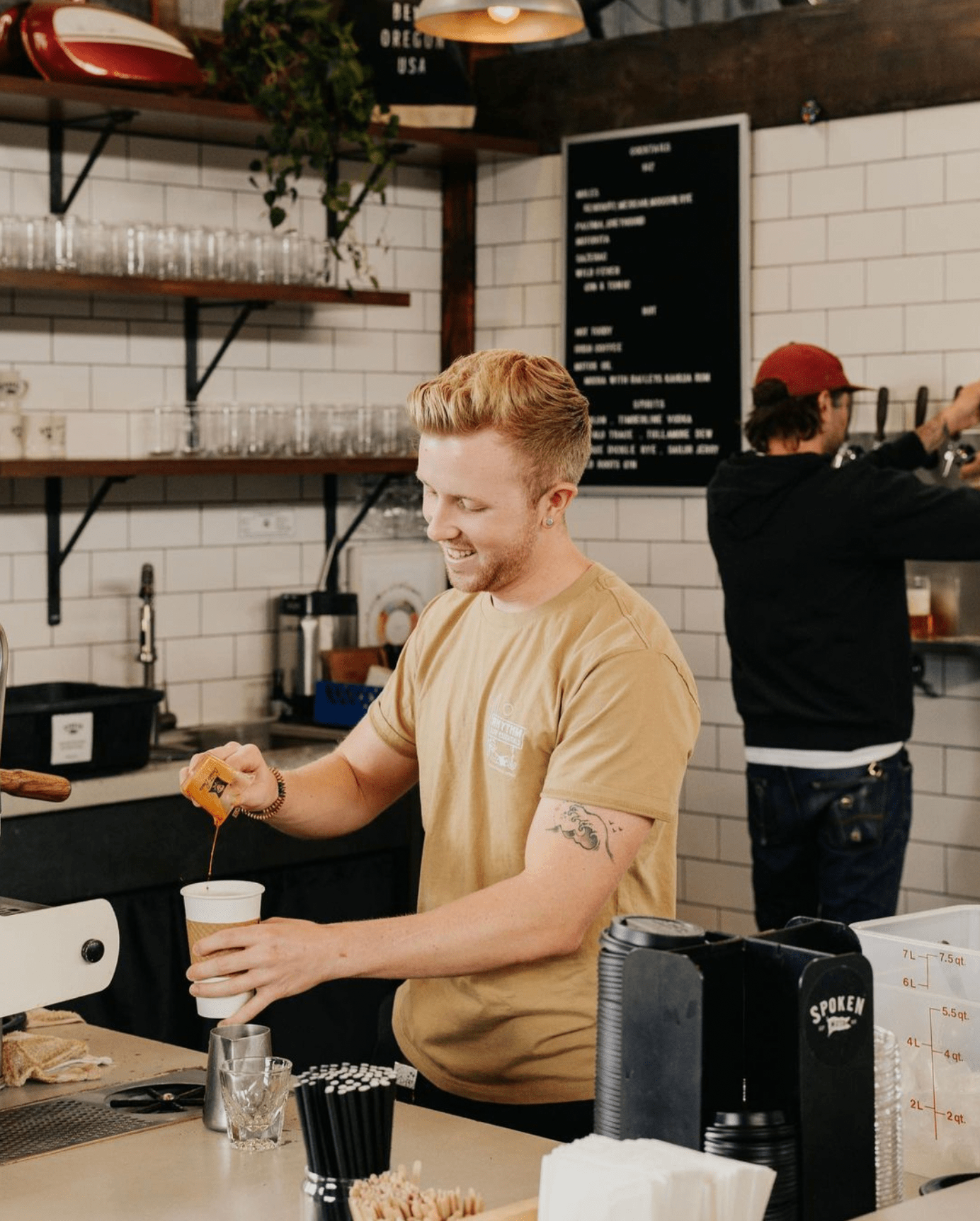 A barista pouring coffee into a cup in a coffee shop.