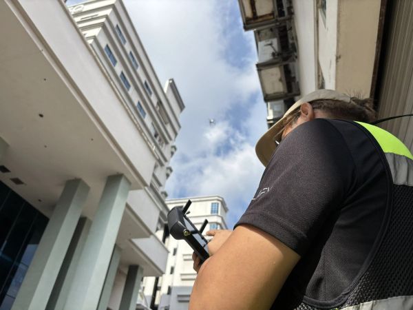 Technician operating a drone controller outside a building