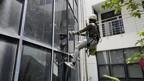 Rope access technician inspecting a glass curtain wall facade