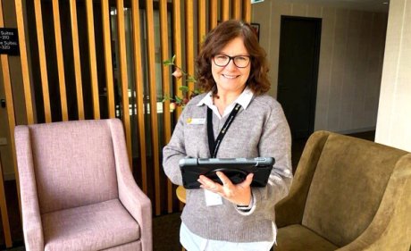 Clinical manager Juliet stands in reception with an tablet in hand