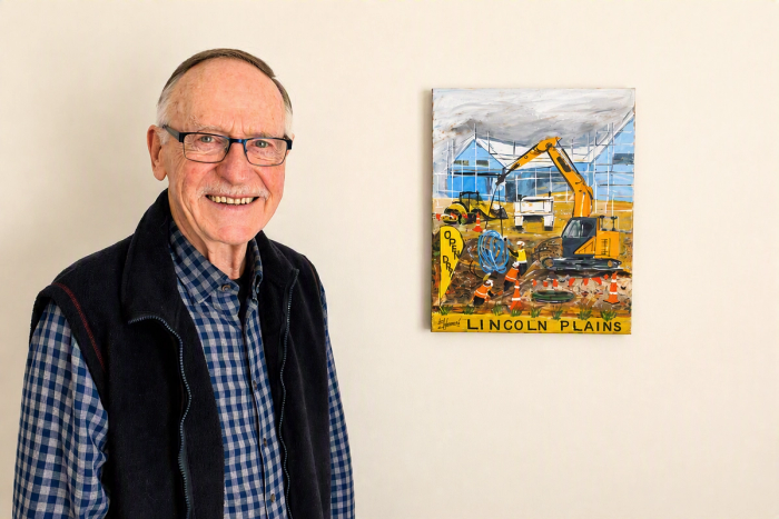 elderly resident stands next to painting of development at Lincoln Plains