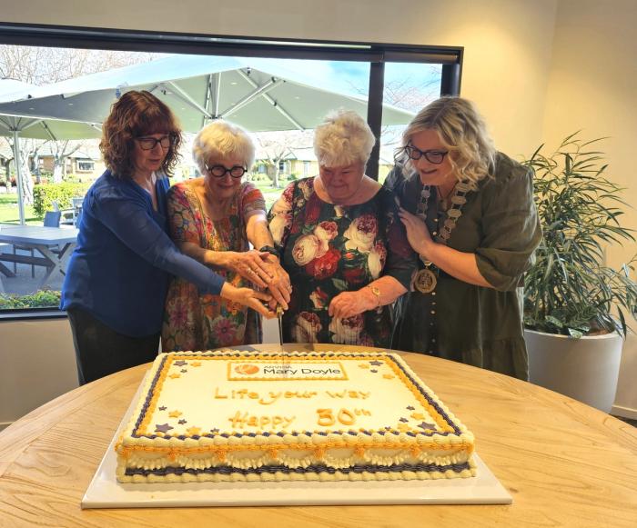 Four ladies cutting a cake to celebrate 30 yrs of Mary Doyle