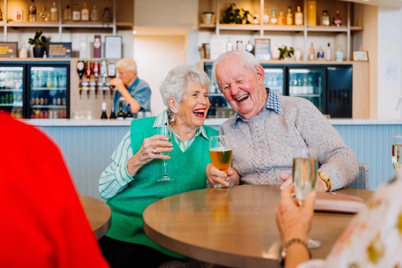 Older couple sharing a drink and laughing at the Bethlehem Country Club