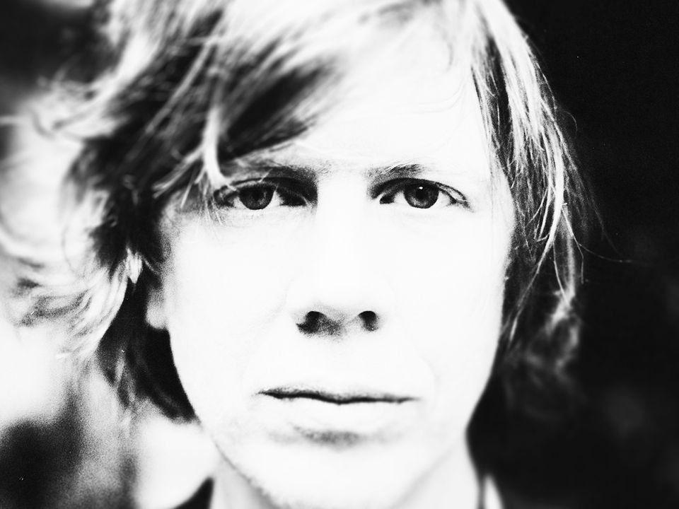 A close up image of Thurston Moore, looking directly into the camera. 