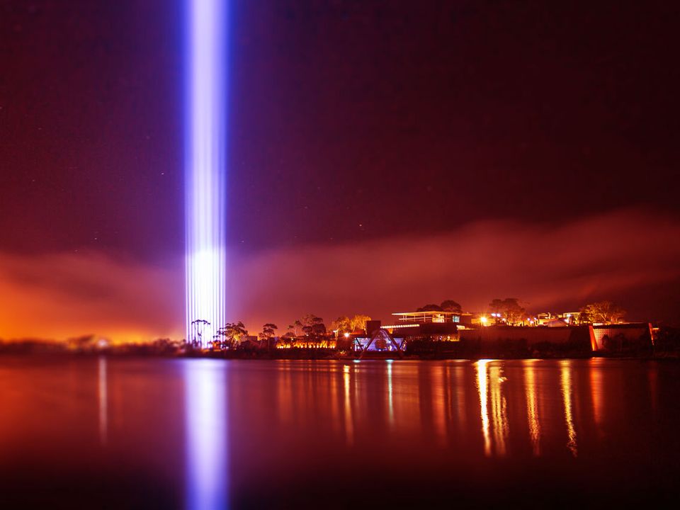 A great pillar of light reaching into the night sky, being reflected onto the Derwent River.