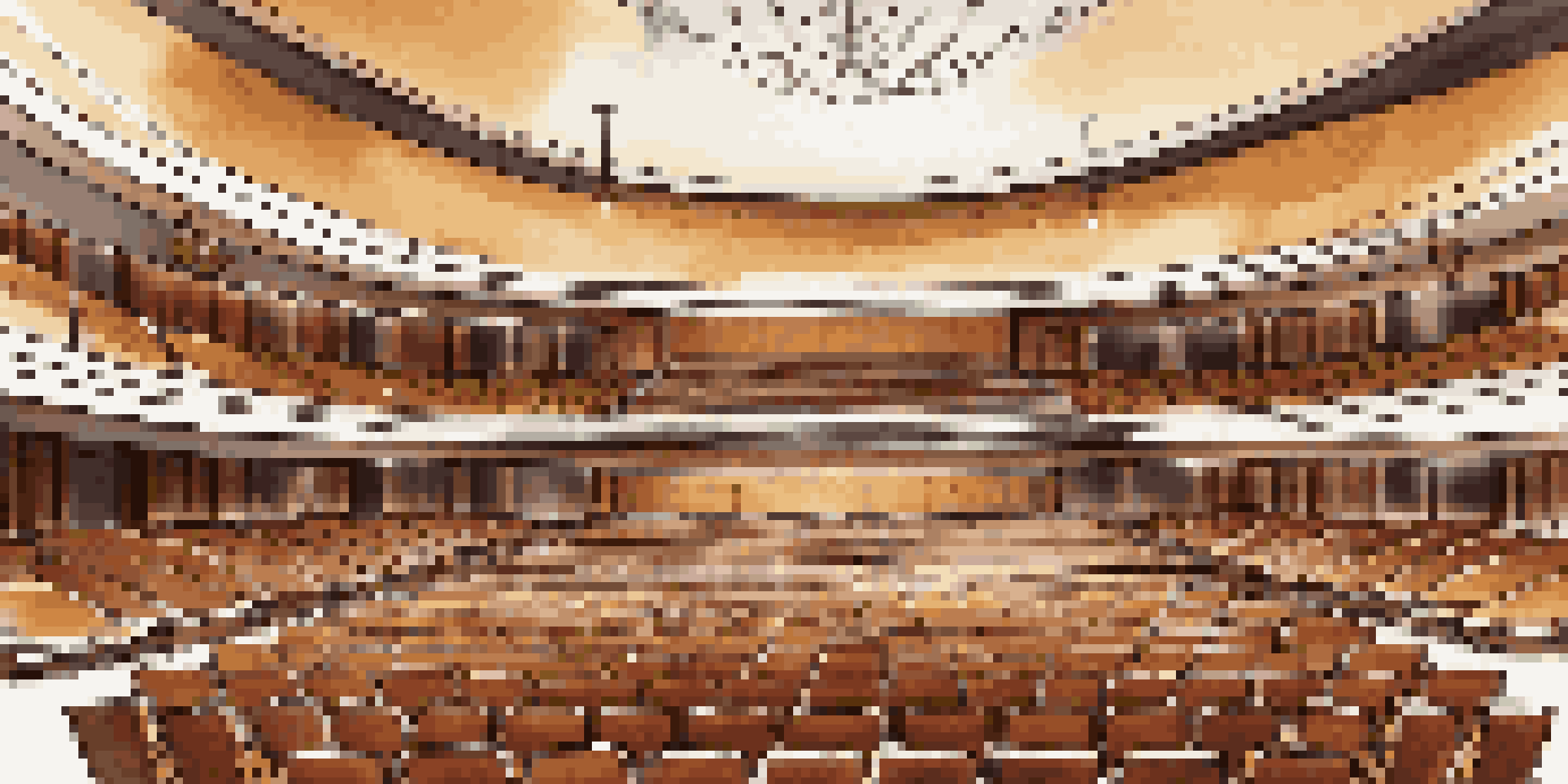 An elegant concert hall interior with a fan-shaped layout, plush seating, wooden acoustic panels, and a well-lit stage area with musical instruments.