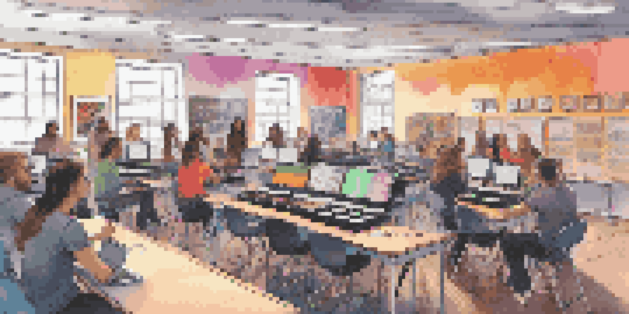A lively classroom where students are actively engaged in music production using laptops and software, with vibrant colors and motivational posters in the background.