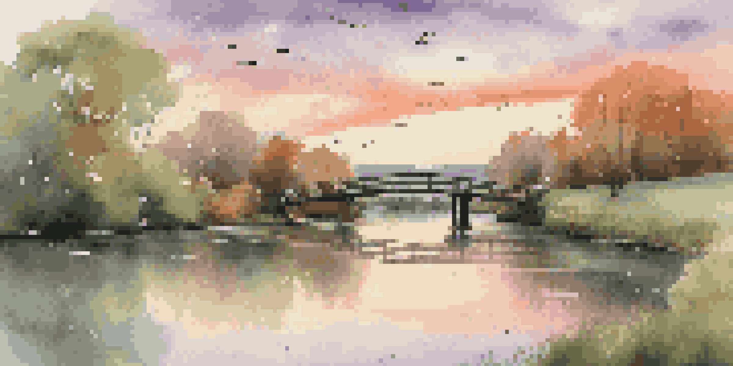 A peaceful sunset over a river with green trees and a wooden bridge, showcasing warm colors in the sky.