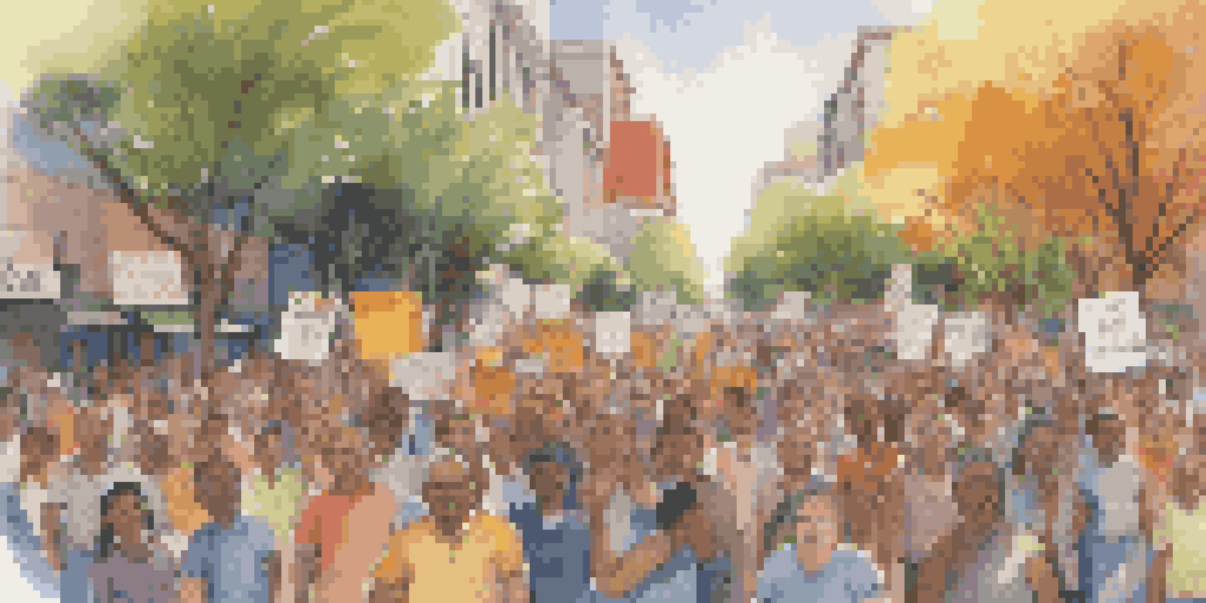 A lively public protest with diverse people holding signs and chanting in a city street, under warm sunlight.
