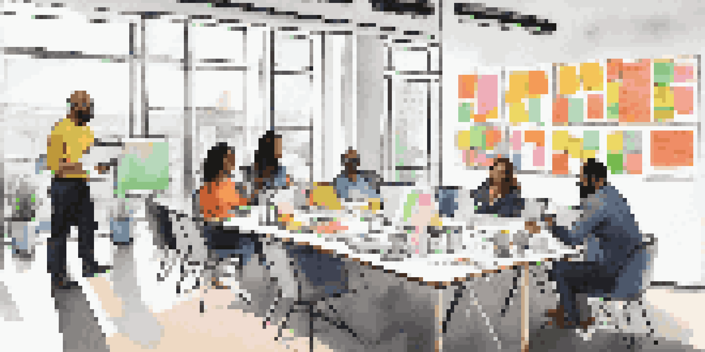 A diverse group of event planners collaborating in a bright, modern office, with laptops and colorful sticky notes around a large table.