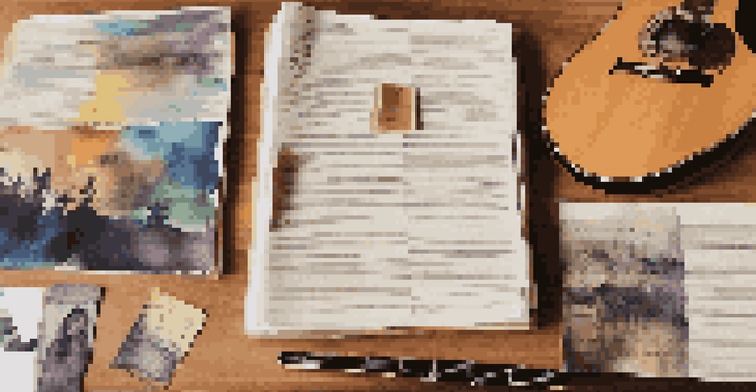 A songwriting portfolio displayed on a wooden desk with album covers and handwritten lyrics, illuminated by soft natural light.