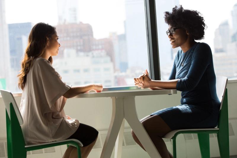 two women sitting beside table talking