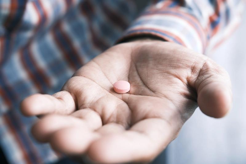 A hand holding a pill