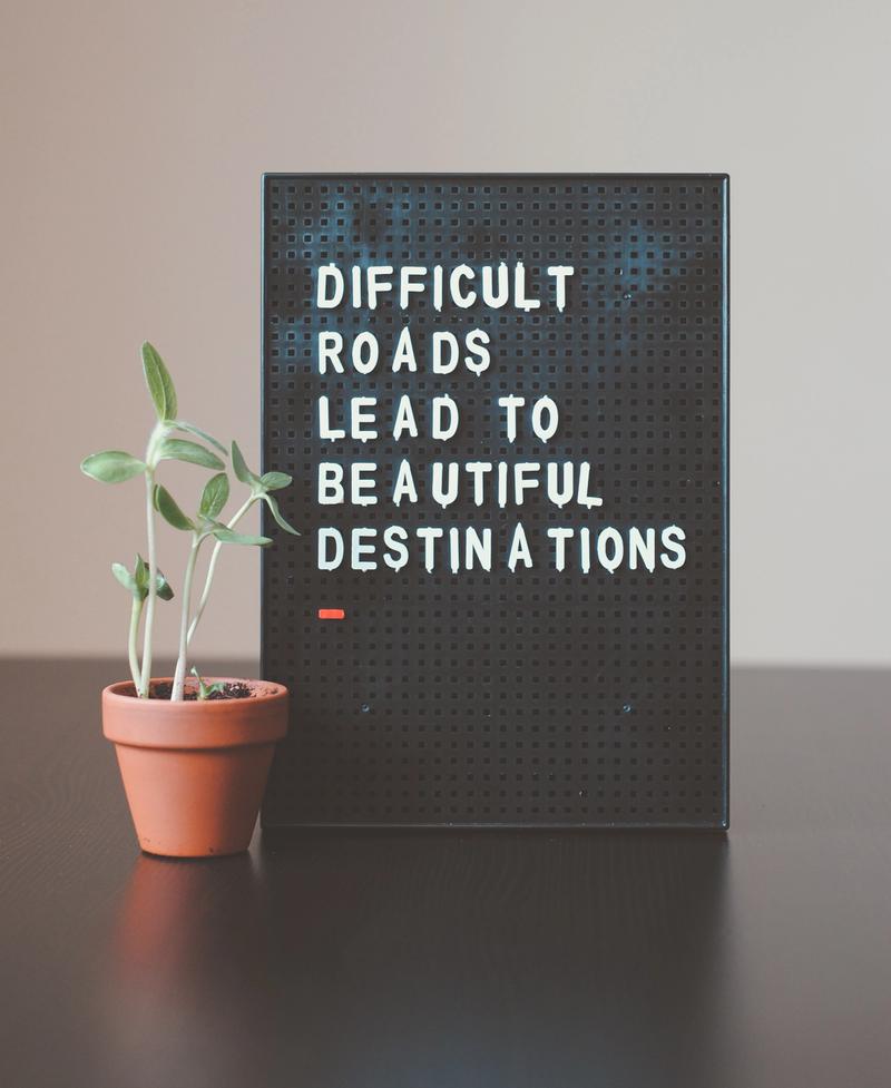 Picture of a board that reads difficult roads lead to beautiful destinations.
