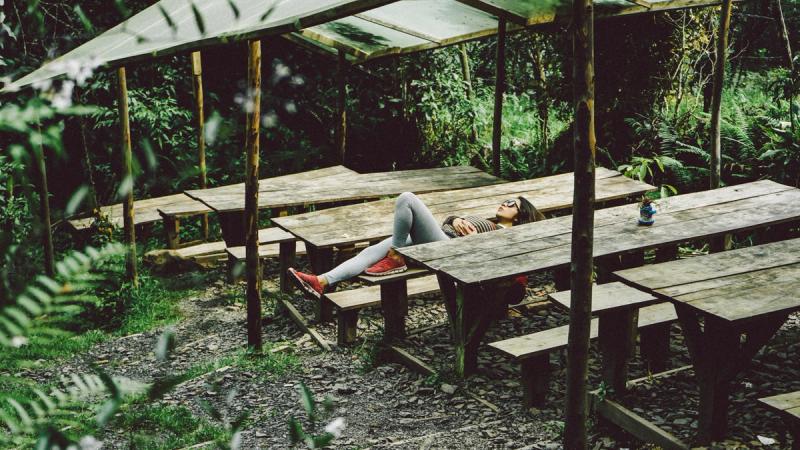 woman lying on grey wooden picnic table