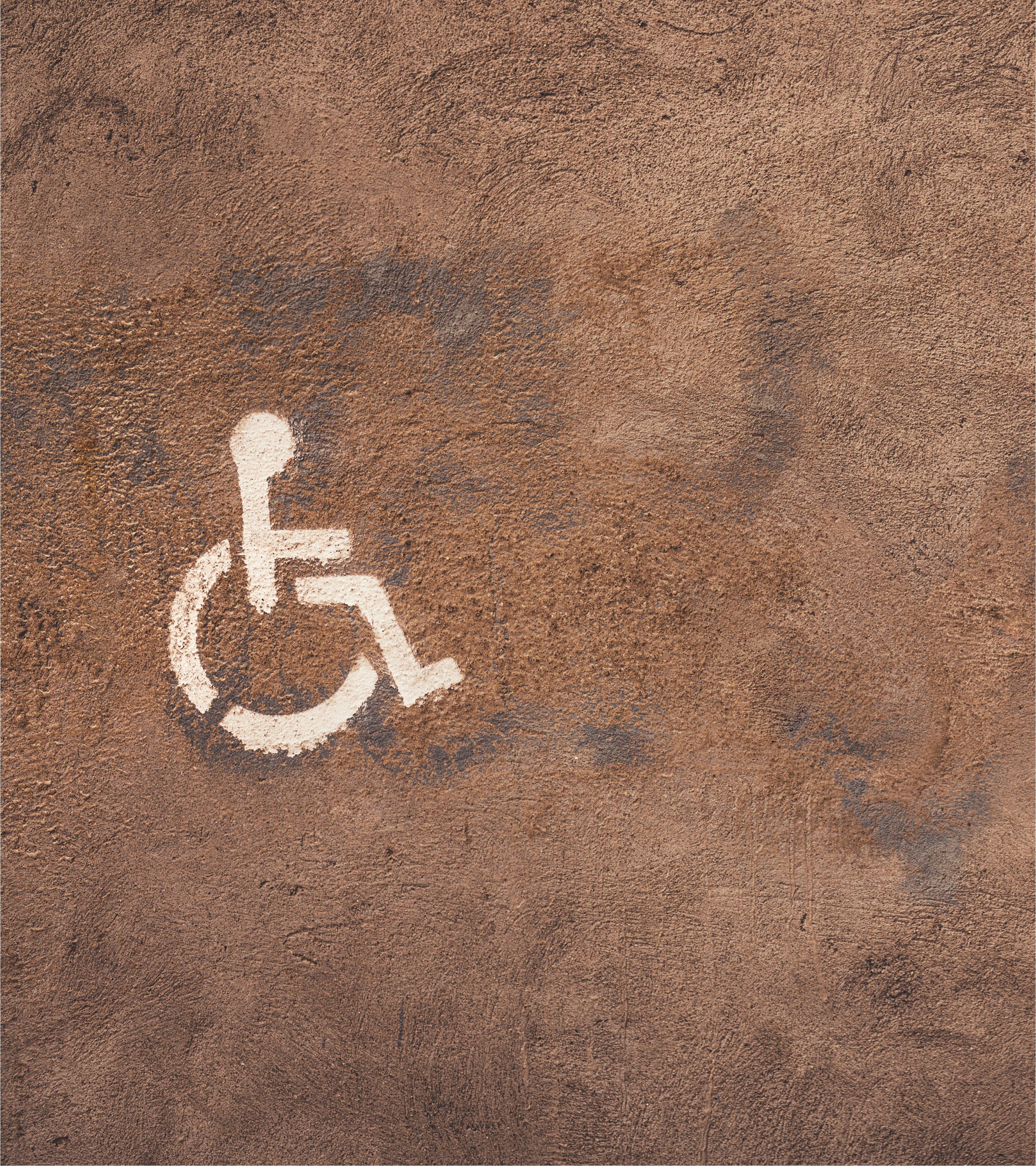 Universal accessibility wheelchair icon painted on textured urban surface