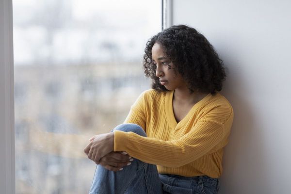 Vrouw zit peinzend tegen een muur