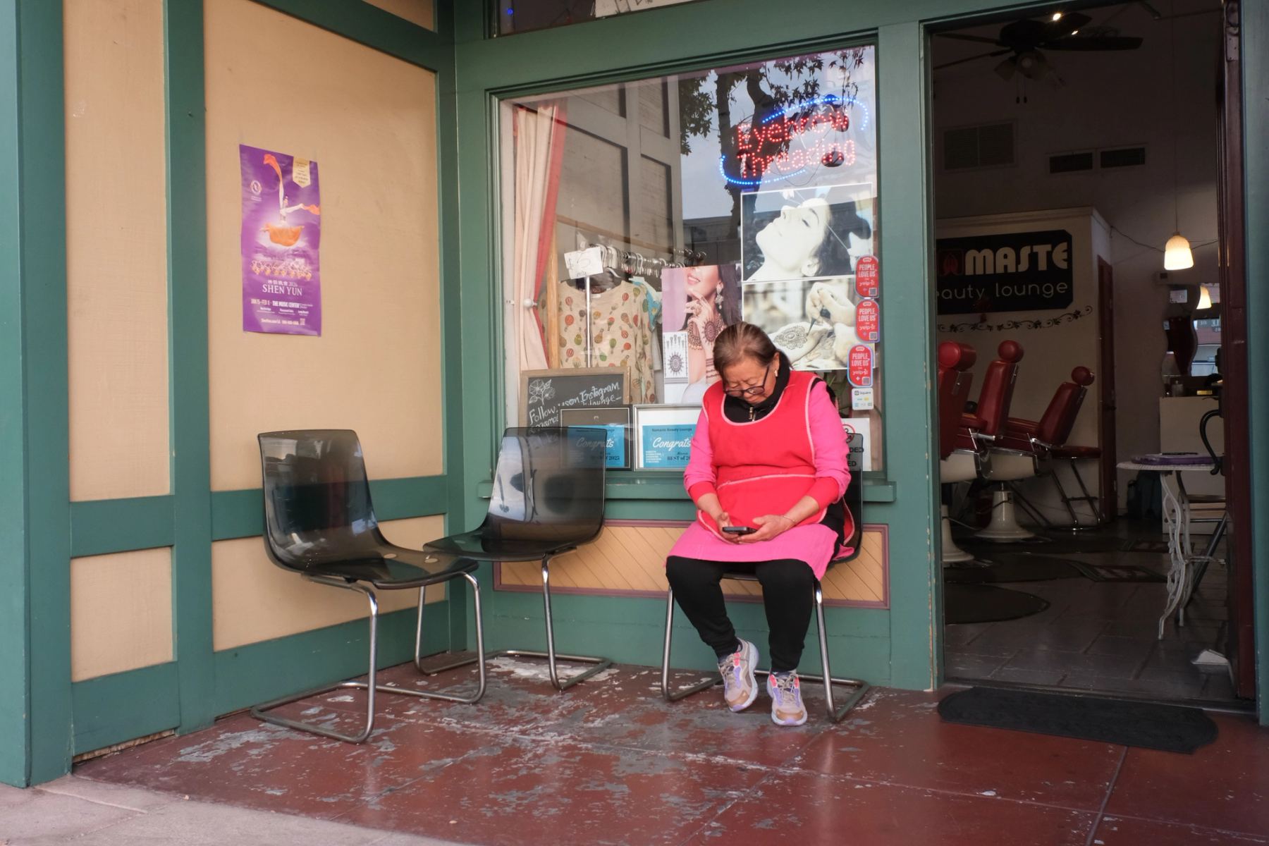 An old lady sitting in front of a salon