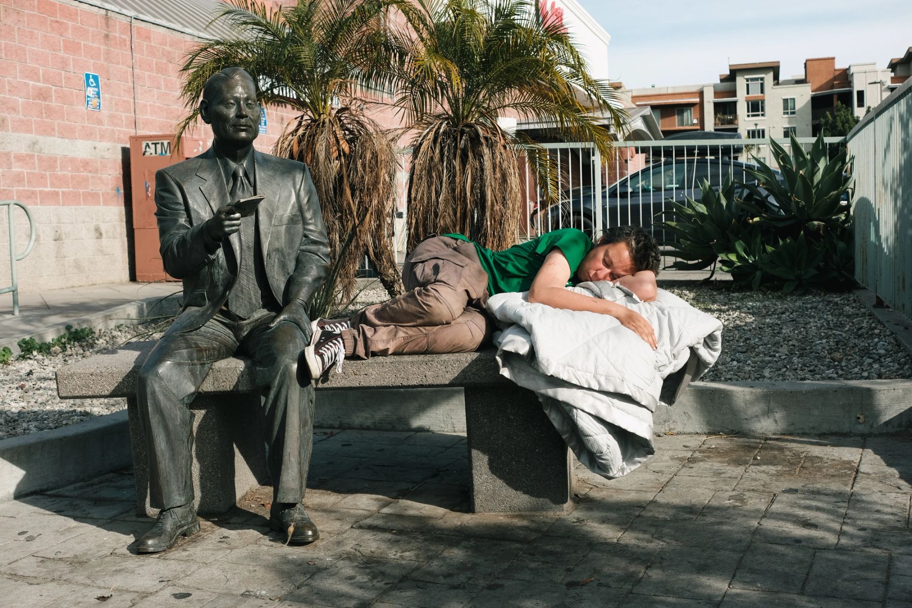 A man lying on a bench next to a sculpture