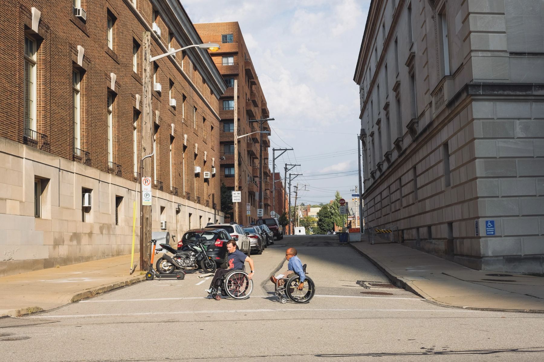 Two disabled people walking using wheel chairs