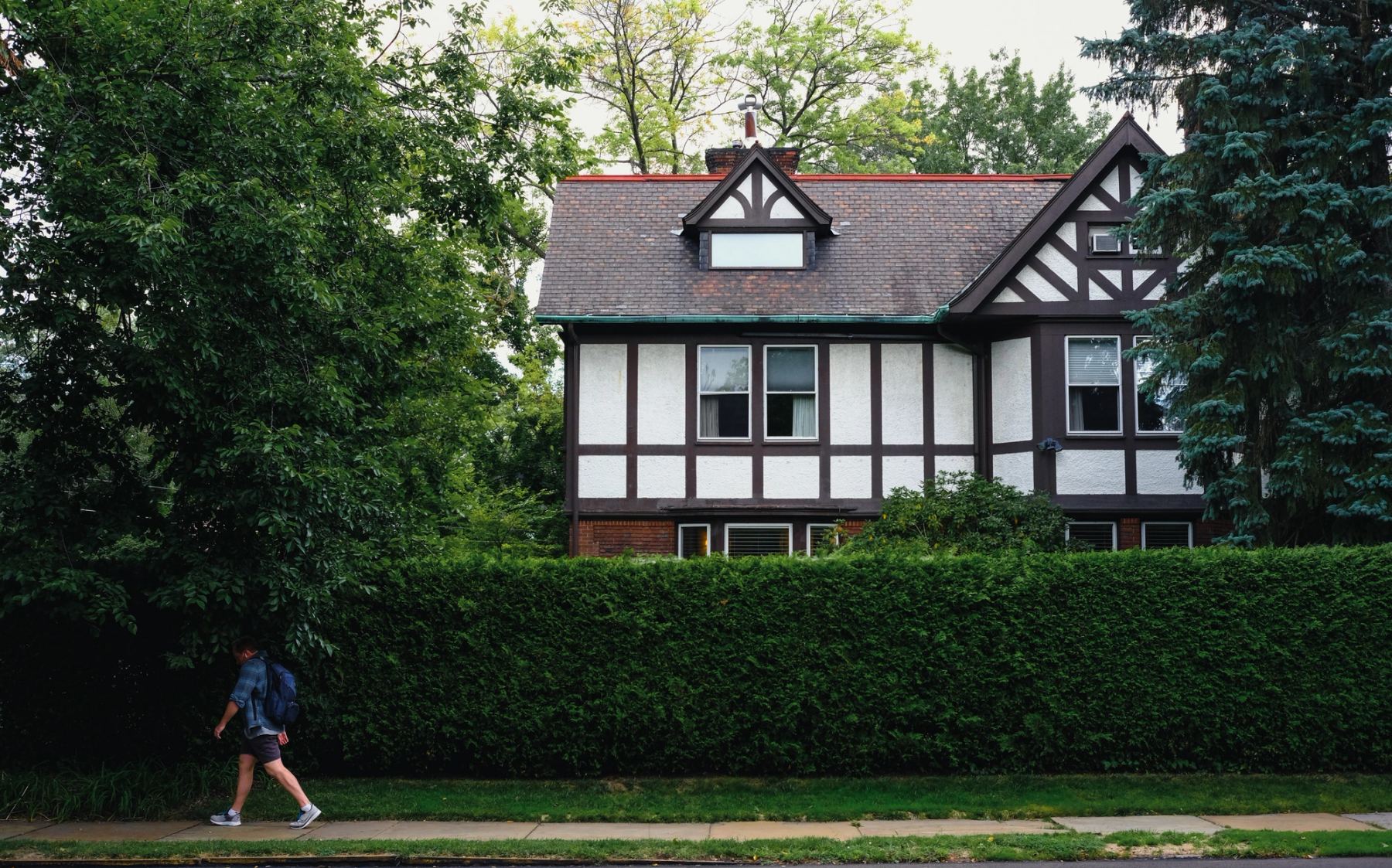 A man walking on the street passing a house