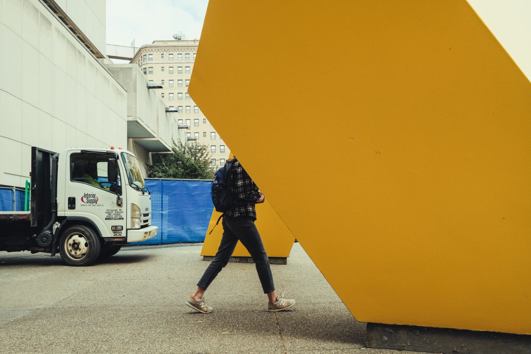 A person walking, upper body blocked by a statue
