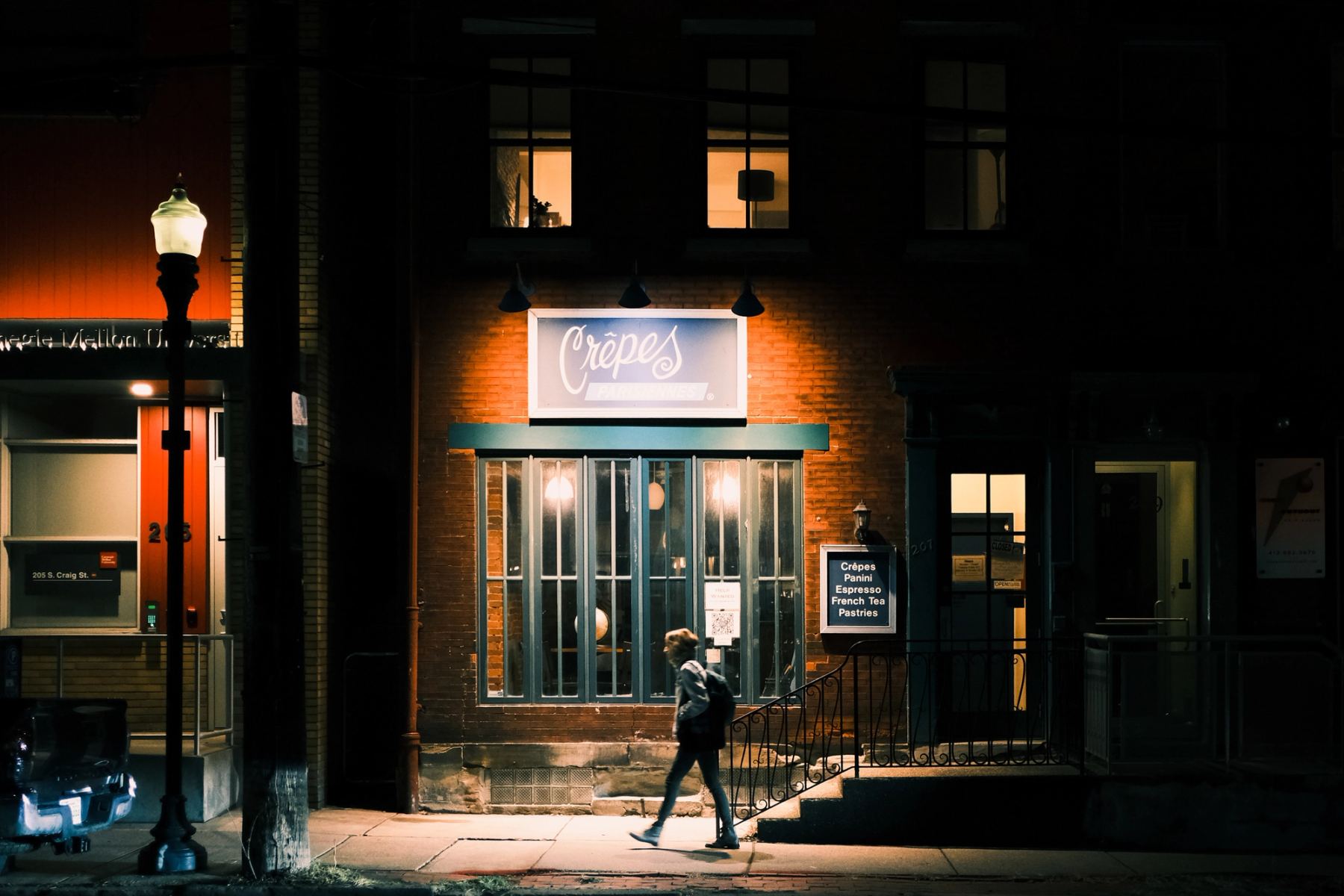 A person walking in a dark street under street lighting