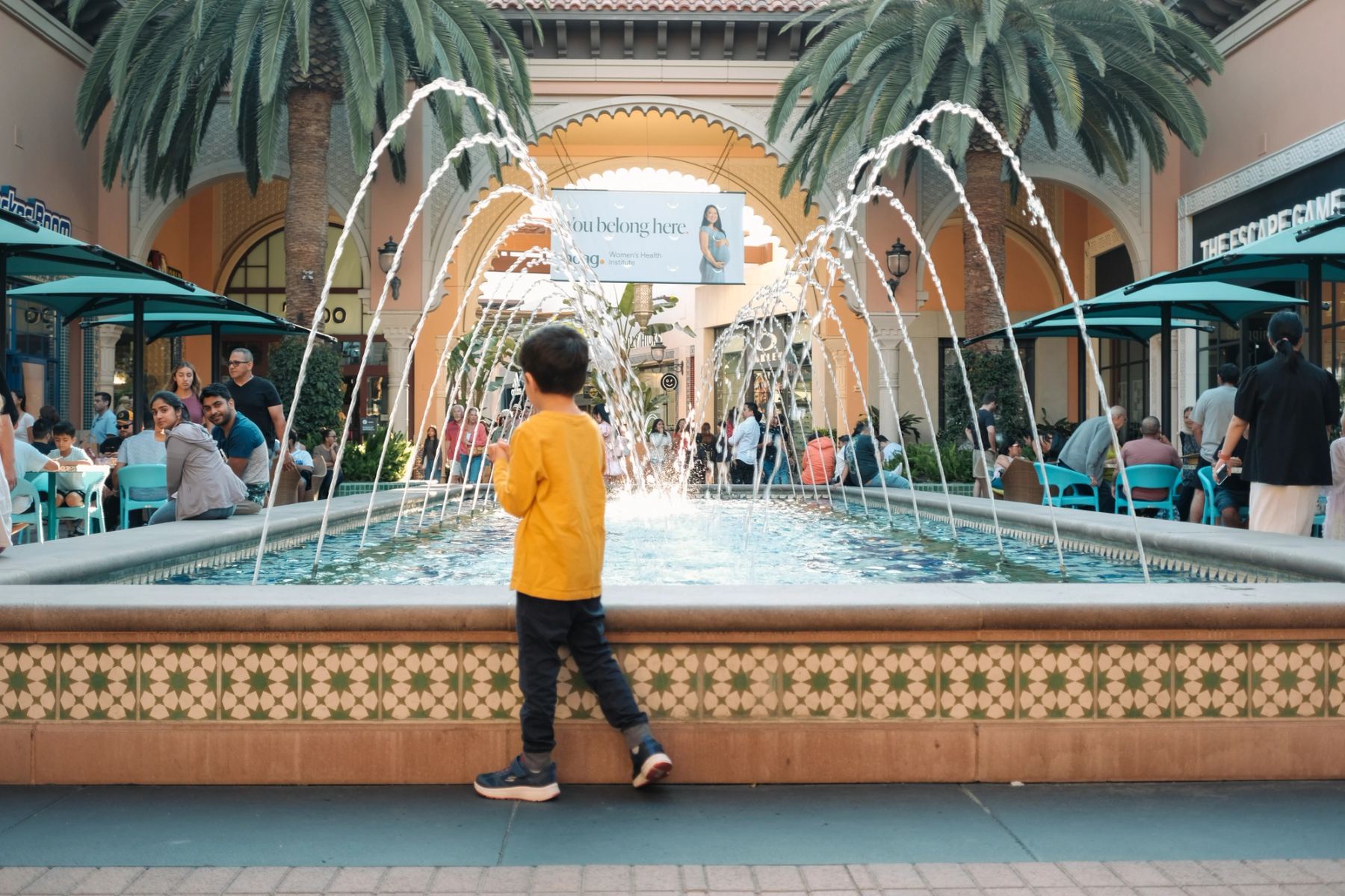 A kid standing next to a fountain pool