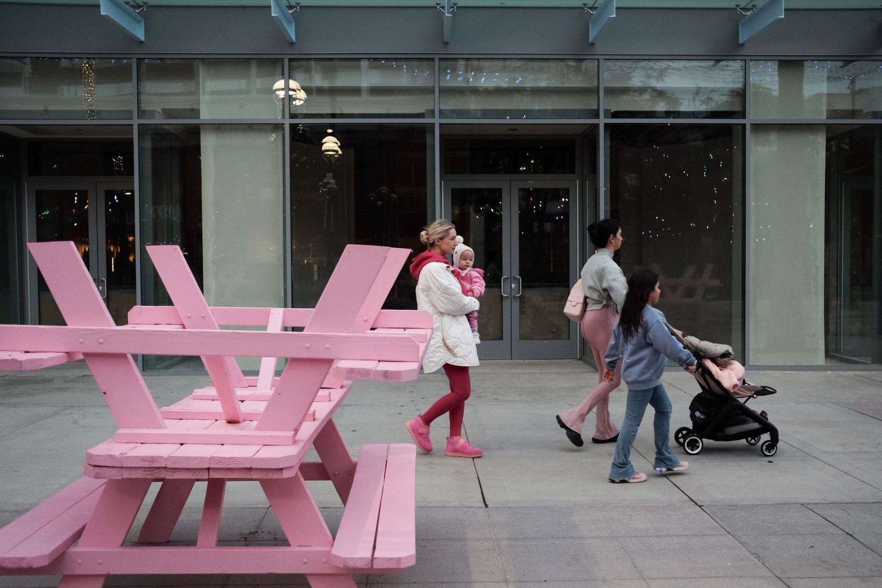 People wearing pink walking past pink tables