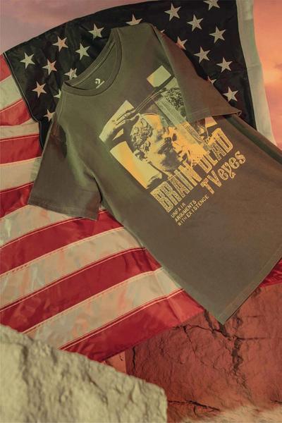 A tshirt sits in front of an american flag. Brain Dead x Converse collaboration.