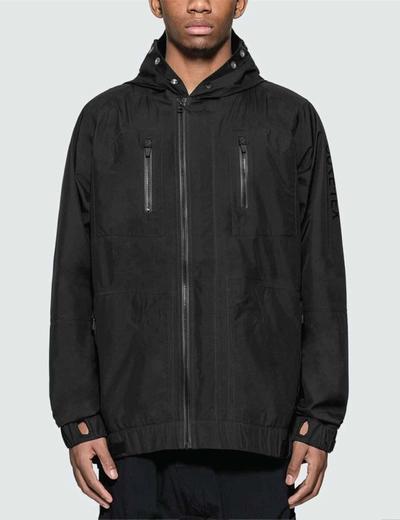 A man standing in a black jacket. Soloist x Converse collaboration.