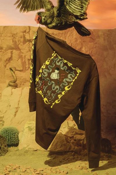 A long sleeve tshirt hangs from the talons of a taxidermy vulture. Brain Dead x Converse collaboration.