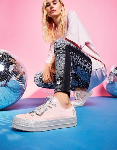 A photo of a woman showing off her shoe. Miley Cyrus x converse collaboration