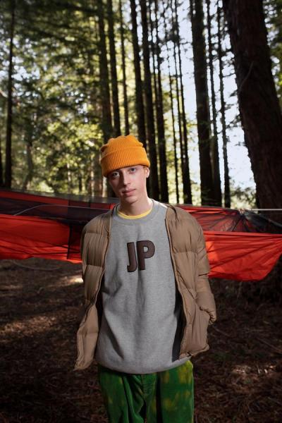 Young white guy standing in front of a hammok in the middle of the forest.