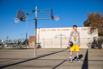 WIDE SHOT OF A LONE BASKETBALL PLAYER ON AN OUTDOOR BBALL COURT