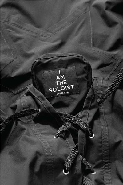 A close up view of a hood with lacing as seen often on a shoe. Soloist x Converse collaboration.