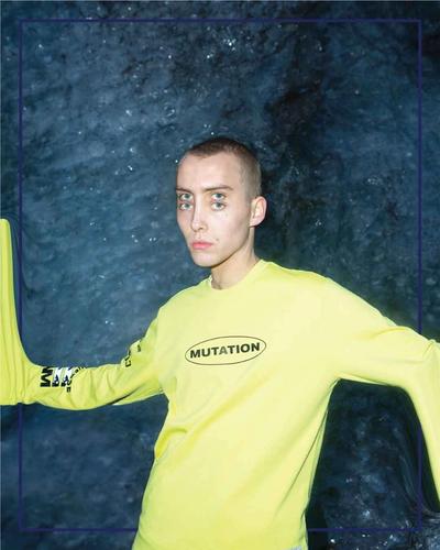 A four-eyed man in a yellow tee w warped parts of his body to appear to mutate. Converse x P.A.M. (Perks and Mini) collab. 