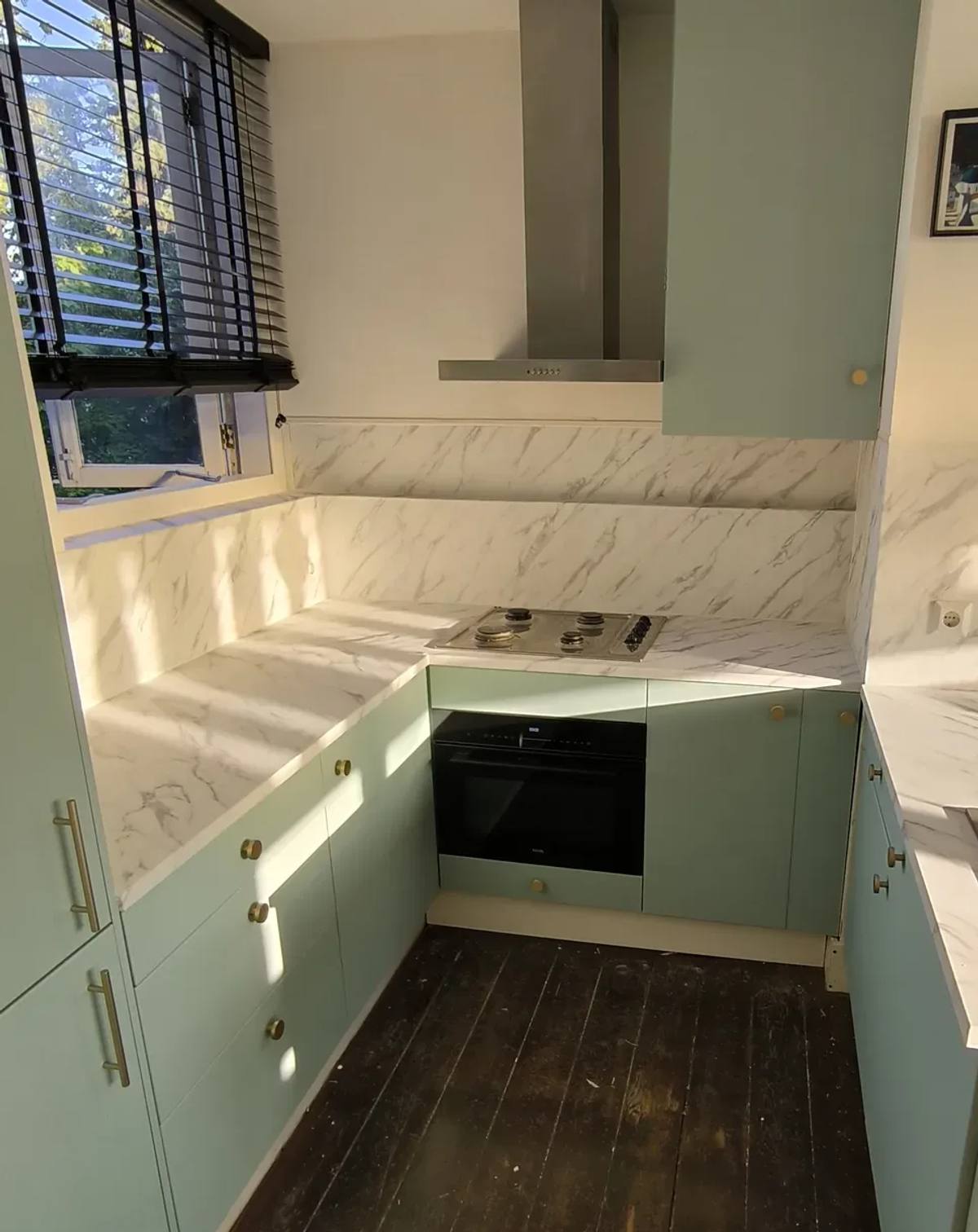 Keuken met frontjes in pistachegroen en een aanrechtblad en achterwand in wit marmer