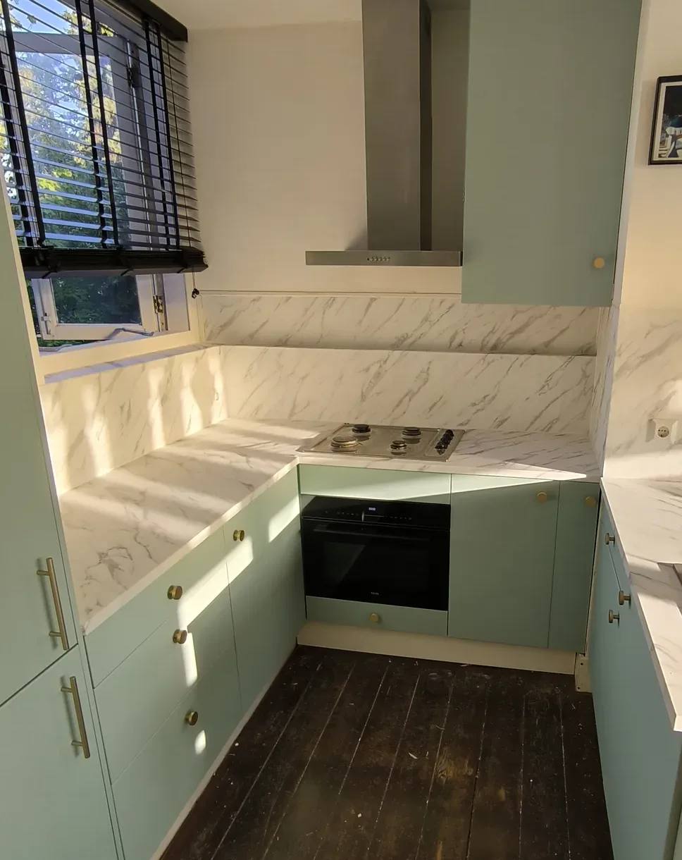 Keuken met frontjes in pistachegroen en een aanrechtblad en achterwand in wit marmer